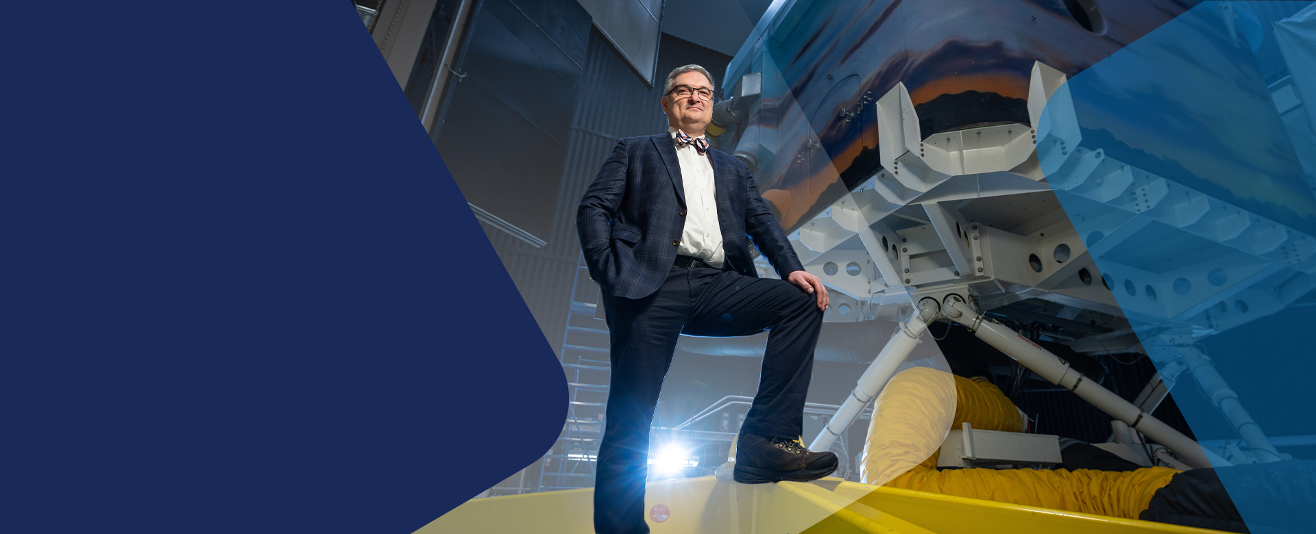 The CEO of KITE Research Institute stands in a suit and bow tie in front of a futuristic research lab