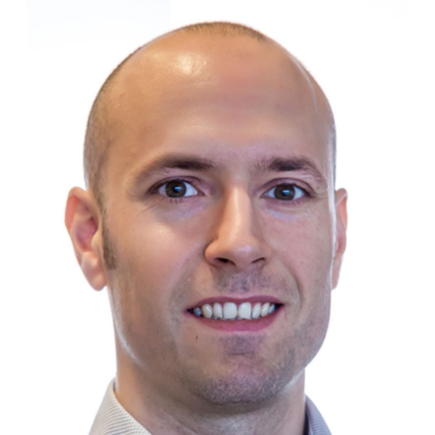 A similing man with a shaved head wearing a dress shirt 
