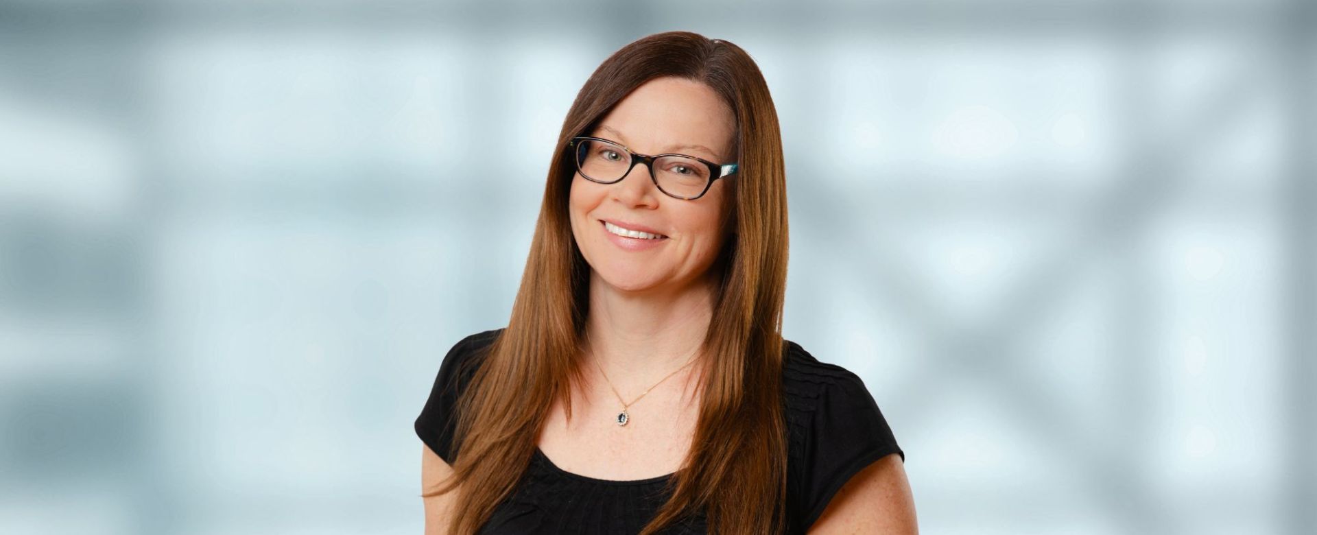 A woman with long hair and glasses in a black shirt. 
