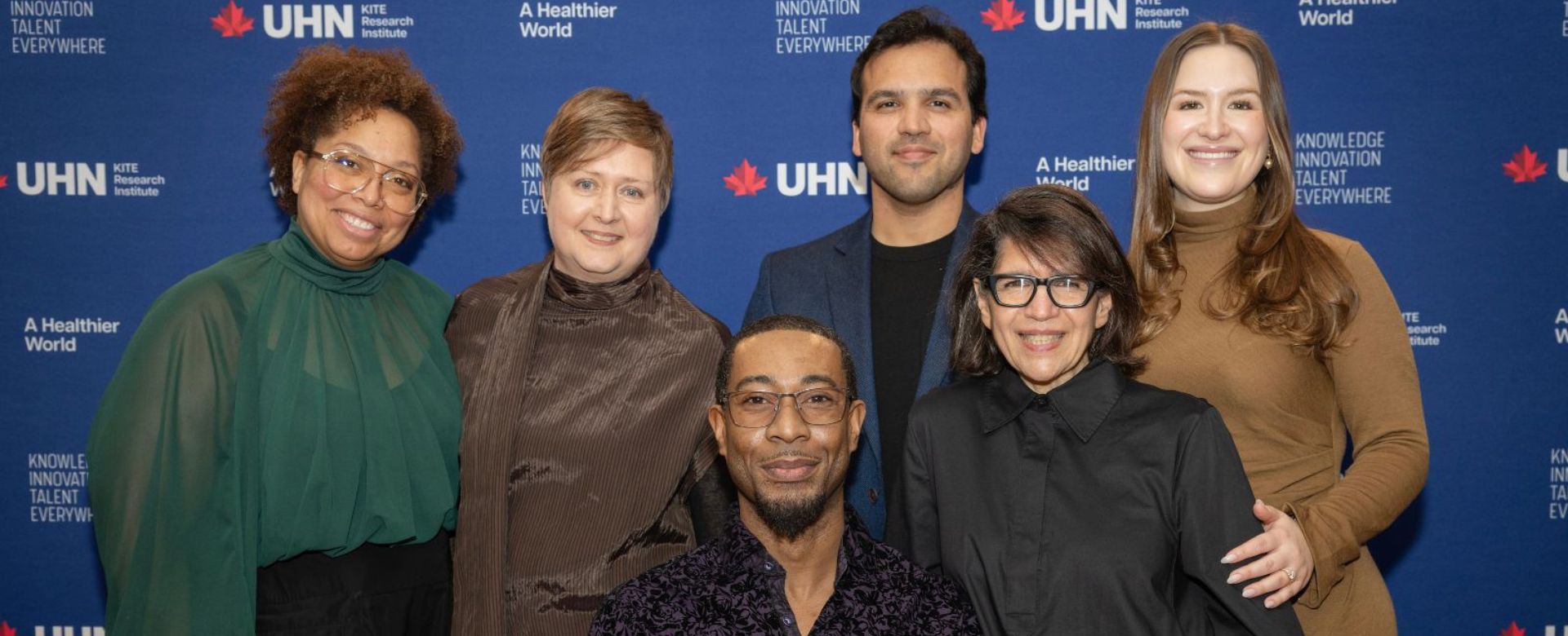 A diverse group of six people in front of a UHN backdrop.