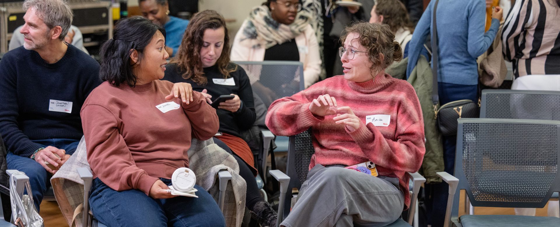 Two people sitting and speaking to each other in an animated way during an event. 