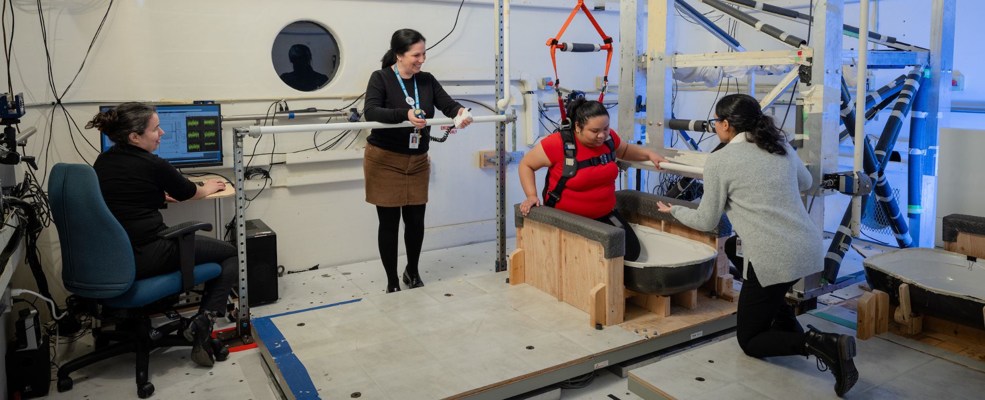 A woman climbs out of a bathtub in a lab while three researchers watch. 